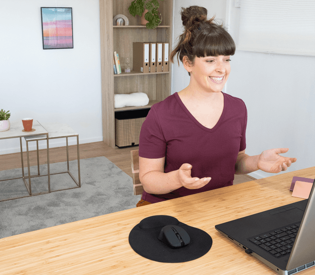 Mujer sentada frente a un escritorio con notebook conectado con Adaptador Bluetooth Trust Myna 5.4