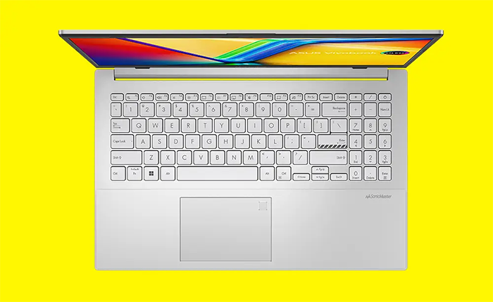 Primer plano del teclado del notebook destacando la tecla Enter, que tiene un borde amarillo brillante distintivo. El teclado es de tipo chiclet con letras negras sobre teclas color plata.