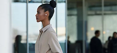 Mujer afroamericana de costado usando los aud&iacute;fonos Sony Wf-C710N-Bz Sony en una oficina