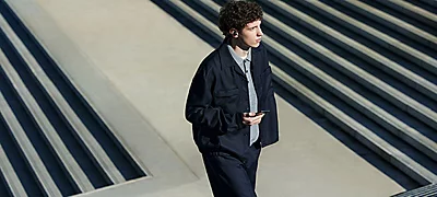 Vista a&eacute;rea de hombre joven con ropa casual usando los aud&iacute;fonos in-ear Sony Wf-C710N-Bz en exterior