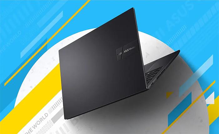 Vista en &aacute;ngulo del notebook semi-cerrado, resaltando el dise&ntilde;o minimalista de la tapa en color negro/gris oscuro con el logotipo de ASUS Vivobook grabado en relieve sobre una placa met&aacute;lica peque&ntilde;a.