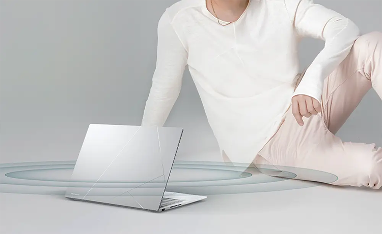 Hombre joven sentado junto a ASUS Zenbook 14 OLED destacando su capacidad de audio
