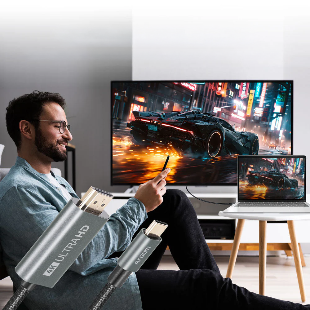 Hombre sentado en living disfrutando la calidad 4k conectando notebook a televisor com cable ArgomTech HDMI a Tipo-C