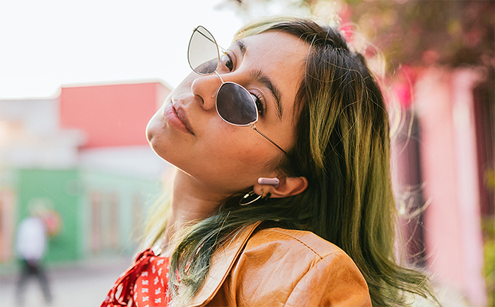 Mujer joven usando los aud&iacute;fonos JBL Wave Beam 2 en exterior para llamadas m&aacute;s claras