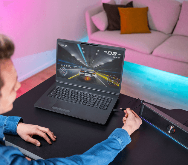 Parlante GXT 619 THORNE siendo utilizado con un notebook, destacando su facilidad de conexi&oacute;n por medio de cable USB o auxiliar