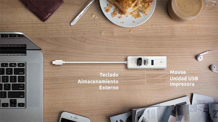 Vista superior de adaptador USB-C a Ethernet Gigabit sobre escritorio acompa&ntilde;ado de varios dispositivos compatibles: notebook, celular, unidad flash, etc