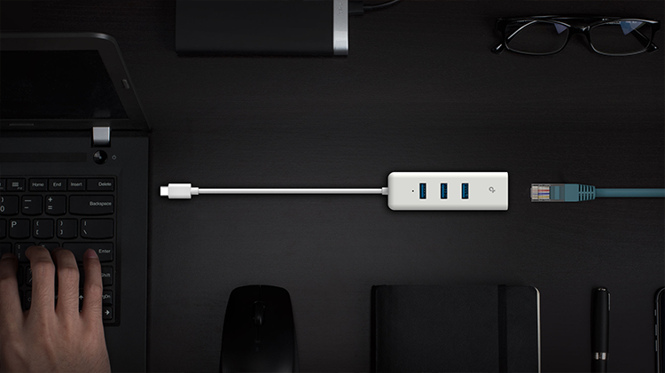 Vista superior de adaptador USB-C a Ethernet Gigabit sobre escritorio elegante acompa&ntilde;ado de varios dispositivos disponibles: cable ethernet, notebook, mouse