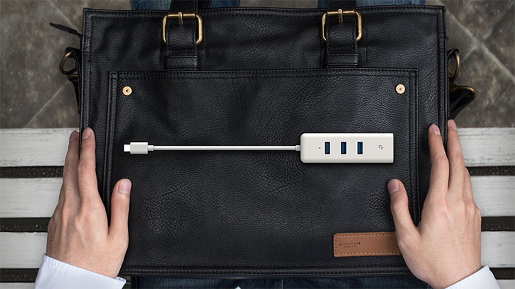 Vista superior adaptador USB-C a Ethernet Gigabit sobre malet&iacute;n destacando sus puertos USB y entrada Ethernet