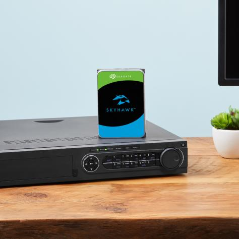 Vista superior completa del disco duro interno Seagate SkyHawk de 14 terabytes. Muestra la carcasa met&aacute;lica plateada con su etiqueta principal blanca, azul y negra, donde se aprecia el logotipo del halc&oacute;n de SkyHawk y las especificaciones t&eacute;cnicas del producto.